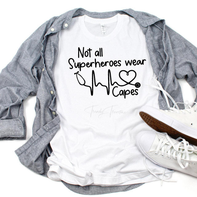 Not all superheroes wear capes stethoscope heartbeat sublimation transfer T-shirt, white T-shirt with black text and stethoscope graphic print, casual style, paired with a gray shirt and white sneakers.