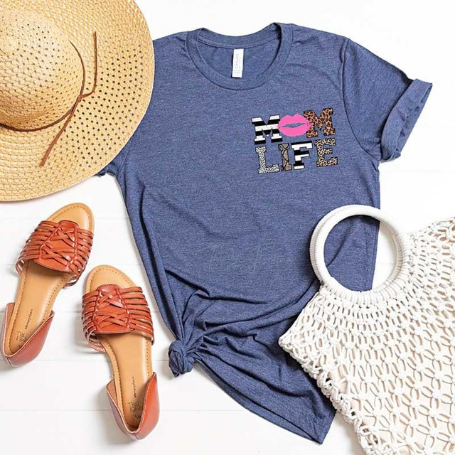 Mom Life HAT/POCKET Screen Print Transfer, blue T-shirt with leopard and lips design, summer accessories including a straw hat, tan sandals, and a white woven bag.