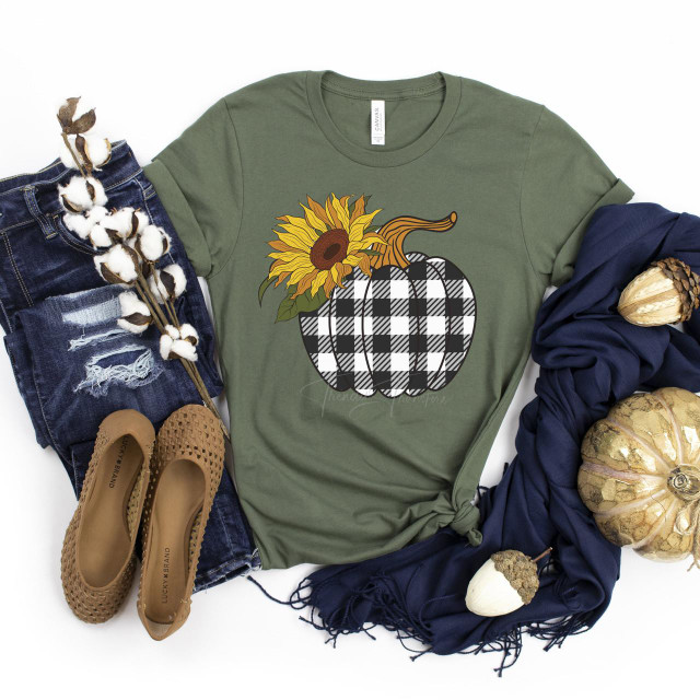 Plaid Pumpkin Screen Print Transfer, green t-shirt with sunflower and pumpkin design on it, surrounded by denim jeans, beige woven shoes, navy blue scarf, and decorative pumpkins for fall or Halloween celebration.