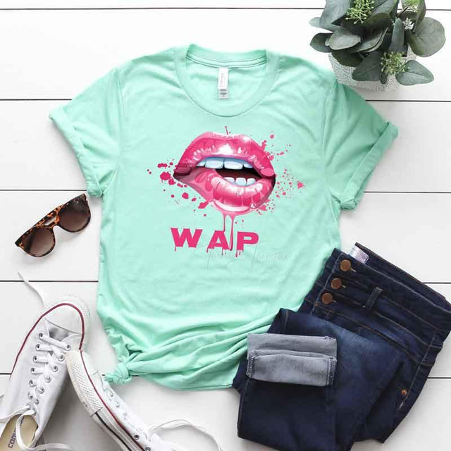 Wet Lips Screen FINAL STOCK Print Heat Transfer, mint green t-shirt with graphic of lips and the word WAP, casual clothing laid out with sunglasses, jeans, and sneakers on a white wooden surface.