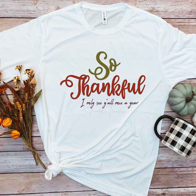So Thankful Sublimation Transfer, white T-shirt with thankful design and quote, fall decorations, and pumpkin on wooden surface.