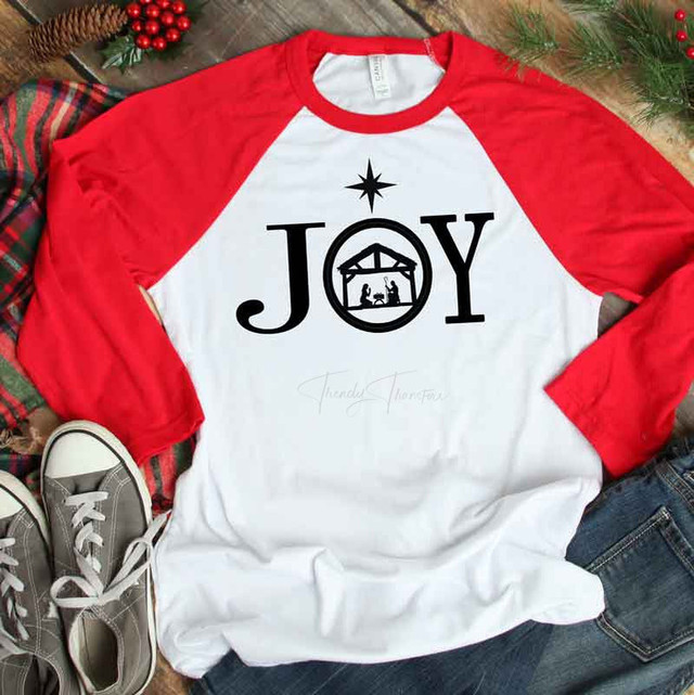 JOY Sublimation Transfer, Christmas-themed T-shirt with red sleeves and a graphic of a nativity scene inside a circle, topped with a star.