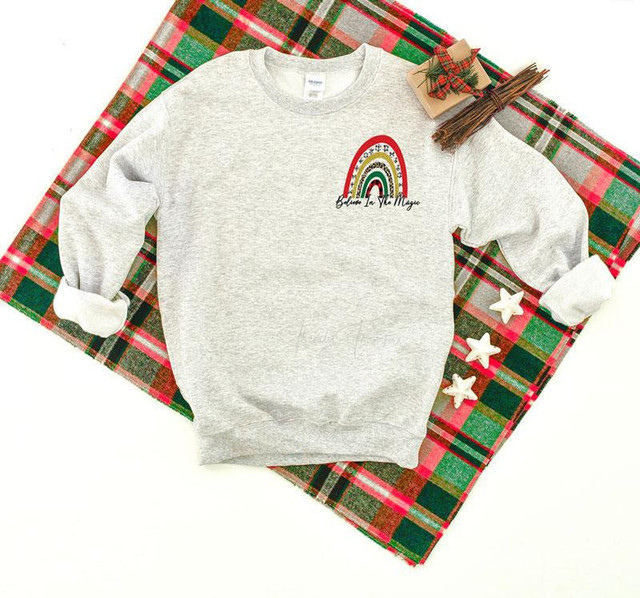 Believe In The Magic Rainbow Pocket Screen Print Heat Transfer, a colorful rainbow design with stars on a gray sweatshirt.