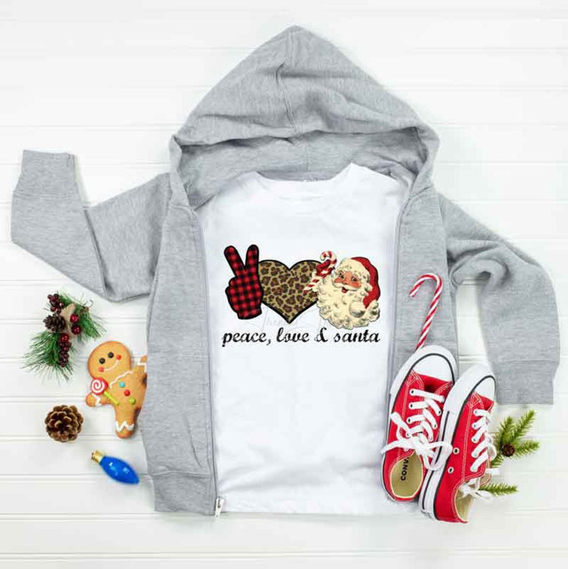 Peace Love Santa Sublimation Transfer, festive Christmas-themed clothing and accessories display with a t-shirt featuring holiday graphics, red sneakers, and holiday decorations.