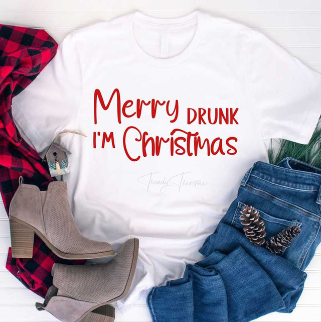 Merry Drunk I'm Christmas Sublimation Transfer, white T-shirt with red text, casual winter outfit with boots, jeans, pinecones, and plaid scarf.