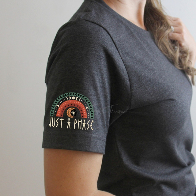 Just a Phase Rainbow HAT/POCKET Screen Print Heat Transfer, colorful rainbow design with the text 'Just a Phase' on a dark gray t-shirt sleeve.