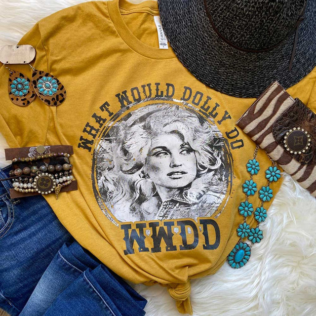 What Would Dolly Do Screen Print Heat Transfer, a graphic t-shirt with a portrait of Dolly Parton, fashion accessories including turquoise jewelry, a woven hat, and striped bandana, laid out on a soft surface for display.