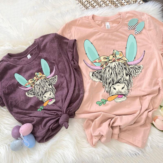 Shaggy Cow Easter YOUTH Screen Print Heat Transfer, colorful cartoon distressed dogs' face with bunny ears, bow, and carrot print on pastel pink and purple t-shirts for Easter holiday.