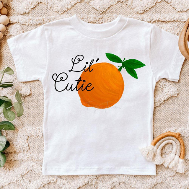 Lil' Cutie Sublimation Transfer, orange fruit design with green leaves on a white children's T-shirt.