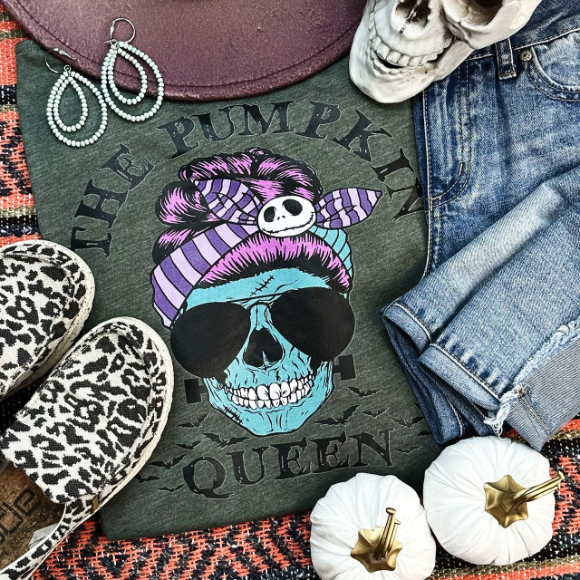 The Pumpkin Queen Screen Print Heat Transfer, colorful skull design with Halloween theme, purple bandana, sunglasses, and skeleton face, on a dark gray T-shirt surrounded by accessories and decor.
