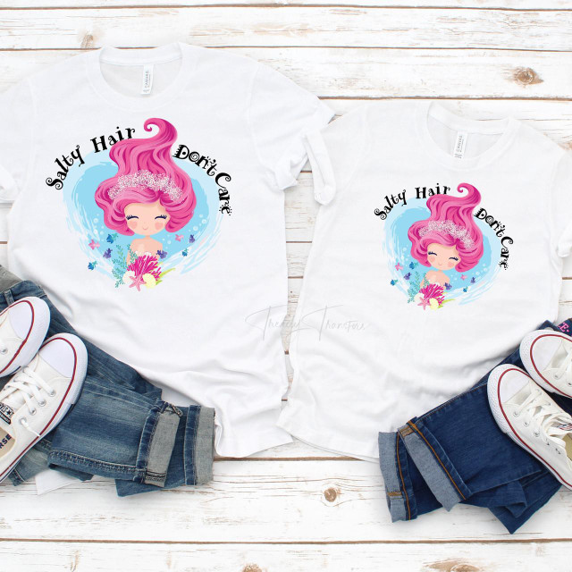 Salty Hair Don't Care Mermaid Summer Sublimation Transfer, pair of white T-shirts with pink-haired mermaid design and the text 'Salty Hair Don't Care', laid flat with sneakers and denim shorts on a white wooden surface