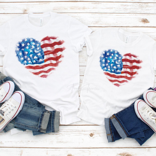 Patriotic Watercolor Flag Heart Sublimation Transfer, showcasing two white t-shirts with a watercolor American flag heart design on a white wooden background.
