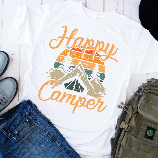 Happy Camper Camping Mountain Sublimation Transfer, white T-shirt with mountain and lake graphic design in sunset colors, camping gear including shoes, jeans, and backpack around it.