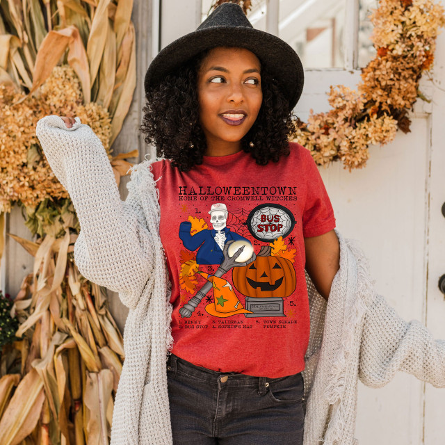 Halloweentown Screen Print Heat Transfer, woman wearing a red Halloween-themed T-shirt with graphic design featuring a skeleton, pumpkin, and autumn leaves.