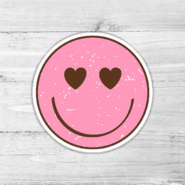 Pink Hearts Smiley Retro Die Cut Sticker, cheerful pink smiley face with heart-shaped eyes and a big smile on a wooden background.