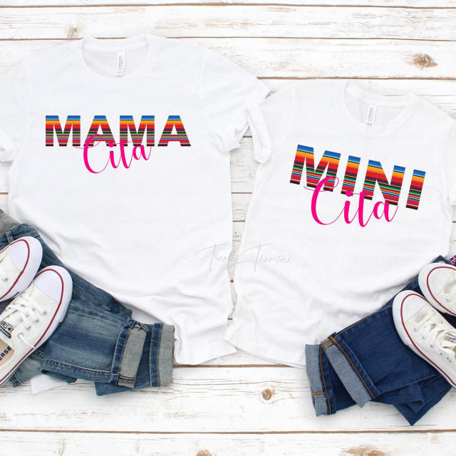 Serape Mini Cita YOUTH and TODDLER Sublimation Transfer, t-shirts with colorful striped text saying 'Mama' and 'Mini' with pink cursive 'Cita' on white fabric, paired with denim shorts and casual sneakers on a rustic white wooden background.