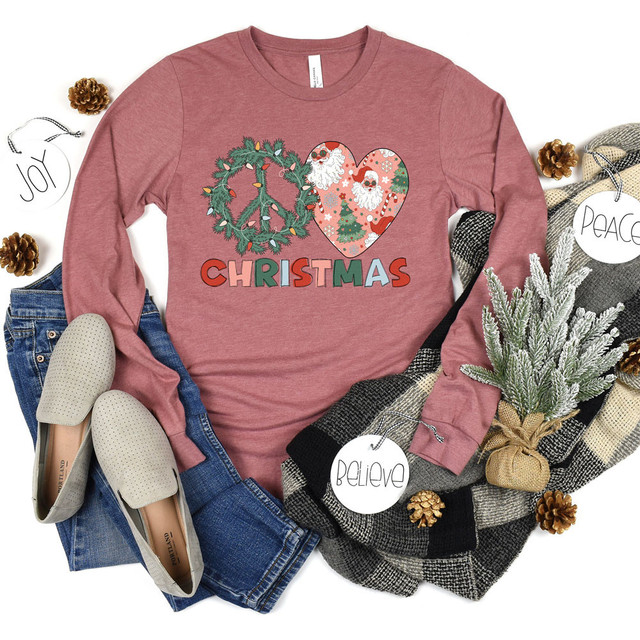Peace Love Christmas DTF Transfer, festive holiday-themed image featuring a pink sweatshirt with Christmas graphics and text, surrounded by cozy winter accessories.