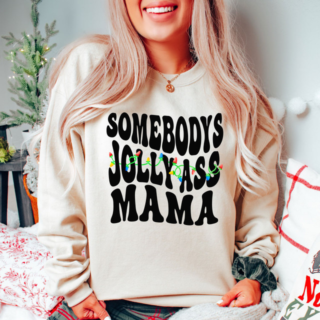 Somebody's Jolly Mama DTF Heat Transfer, festive Christmas-themed design on a beige sweatshirt with Christmas lights decoration.