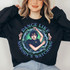 Dance Like Nobody's Watching Screen Print Heat Transfer, person wearing a black sweatshirt with a colorful graphic design of a woman surrounded by skulls and barbed wire, emphasizing the phrase 'Dance Like Nobody's Watching'.