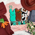 Some Bunnies Problem Screen Print Heat Transfer, colorful bunny design with text on a pink t-shirt surrounded by clothing and decorative items.