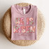 He Is Risen Screen Print Heat Transfer, Pink T-shirt with floral text design for Easter celebration.