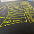 Softball Mama PUFF Screen Print Heat Transfer, close-up view of black fabric with bright yellow outlined lettering and pink softball graphic.