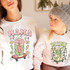 Mama Skateboard Drink DTF Heat Transfer, colorful applied design of a skateboard with a juice box, lightning bolts, stars, and flowers print on a white sweatshirt.