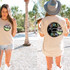 Coconut Drink DTF Heat Transfer, colorful graphic design of a coconut drink with a straw and umbrella on a T-shirt, shown on two women outdoors in a tropical setting.