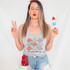 Make America Western Again DTF Heat Transfer, woman holding a popsicle and making a peace sign, wearing a tank top with cowboy hats, and patriotic accessories.