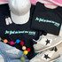 God So Loved The World PUFF Back & Front SET Screen Print Heat Transfer, clothing and accessories including black T-shirts with the quote 'for God so loved the world' and John 3:16, white sneakers with star designs, a white cap, colorful earrings, and a multicolored pom-pom garland.
