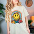 You're More Than Enough DTF Heat Transfer, colorful graphic design featuring a smiling yellow face, rainbow, butterflies, and inspirational words on a woman's t-shirt.