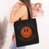 All Are Welcome SIENNA DTF Heat Transfer, black tote bag with orange smiley face and orange text design.