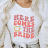 Here Comes The Bride DTF Heat Transfer, white T-shirt with pink lettering and illustration of a wedding ring.