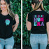 I'm In My Mom Era DTF Heat Transfer, front and back view of a woman wearing a black T-shirt with a colorful graphic and text design that says 'I'm In My Mom Era' featuring a smiling, dripping blue ghost graphic.