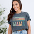 Loved Hardworking Selfless Protective Mama DTF Heat Transfer, in colorful distressed text on a dark gray T-shirt worn by a smiling woman.
