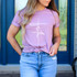 Faith WHITE DTF Heat Transfer, a white graphic design with the word 'faith' written vertically on a light purple t-shirt worn by a woman.