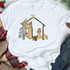 Nativity Scene Screen Print Heat Transfer, image of a Christmas nativity scene illustrated on a white t-shirt with figures of Mary, Joseph, baby Jesus, a manger, a star, and trees.