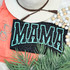 MINT Mama PUFF Screen Print Heat Transfer, black leopard print design with teal outline text reading 'MAMA' on a tropical-themed background with accessories and plants.
