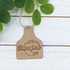 Custom Cardstock Cattle Tags, brown paper tag with printed text and design, tied with a string to a branch with green leaves.