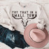 Try That In A Small Town Bullhead DTF Heat Transfer, white sweatshirt with a cow skull graphic and text design placed on a rustic wooden surface with denim shorts and a pink hat.