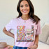 Coffee Gives Me Teacher Powers DTF Heat Transfer, colorful cartoon coffee cup with glasses, smiling and holding books, inspiring teacher-themed design on pink t-shirt.