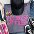 Kindness Is Free NEON Pink Screen Print Heat Transfer, on a gray T-shirt with black sneakers, a black glittery cap, beaded earrings, and colorful woven items around.