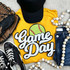 Softball White Game Day Chenille Patch, embroidered patch with a green softball and white 'Game Day' text on a yellow t-shirt surrounded by sneakers, a black cap, and wooden bead necklaces.