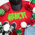 Grinchy Chenille Patch, green fluffy chenille patch spelling out 'GRINCHY' on a red T-shirt among Christmas decorations.
