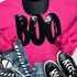 Black BOO Sequin Patch, close-up of a black sequined patch spelling 'BOO' in large letters, placed on a pink sweatshirt with pink sleeves, paired with distressed denim jeans and black sneakers.