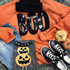 Black BOO Sequin Patch, a shiny black sequin patch spelling 'BOO' on an orange sweatshirt surrounded by Halloween-themed decor including a spooky pumpkin bag, black and white sneakers, and orange fabric pumpkins.