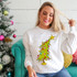 Little Tree DTF Heat Transfer, Christmas tree with colorful ornaments and star on top, on a woman's sweatshirt near a decorated Christmas tree.