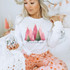 Merry and Bright Trees DTF Heat Transfer, woman wearing Christmas sweatshirts with pink and green holiday trees design.