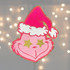 Pink Grouchy Guy Chenille Patch, colorful embroidered patch featuring a pink character with a Santa hat, star-shaped eyes, on a blurred background with lights.