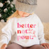 Better Not Pout, DTF Heat Transfer, Christmas themed design on a child's white sweatshirt with a Christmas tree in the background.
